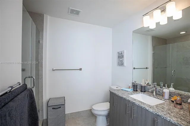 a bathroom with a granite countertop sink a toilet and a mirror