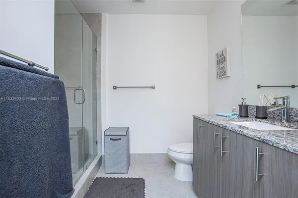 a bathroom with a granite countertop sink a toilet and a shower