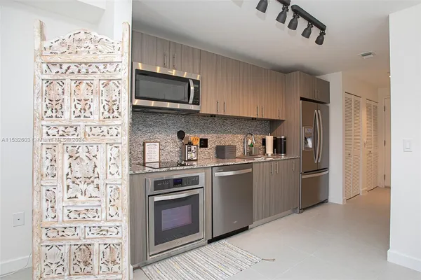 a kitchen with stainless steel appliances granite countertop a refrigerator and a stove top oven