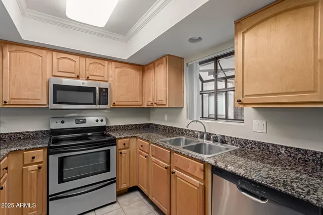 a kitchen with granite countertop a sink cabinets and stainless steel appliances