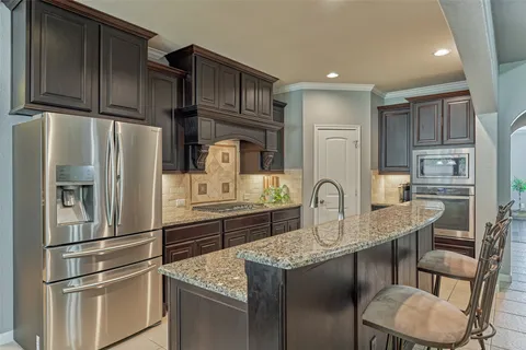 a kitchen with stainless steel appliances granite countertop a refrigerator a stove a sink and a refrigerator
