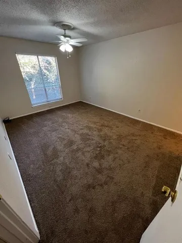 en empty room with windows and ceiling fan