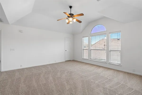 an empty room with chandelier fan and windows