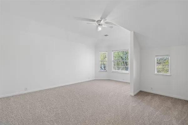 an empty room with windows and fan