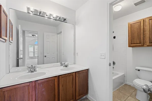 a bathroom with a double vanity sink toilet and mirror
