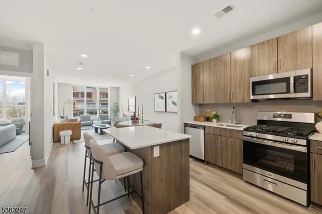 a kitchen with stainless steel appliances granite countertop a stove top oven a sink dishwasher a dining table and chairs with wooden floor