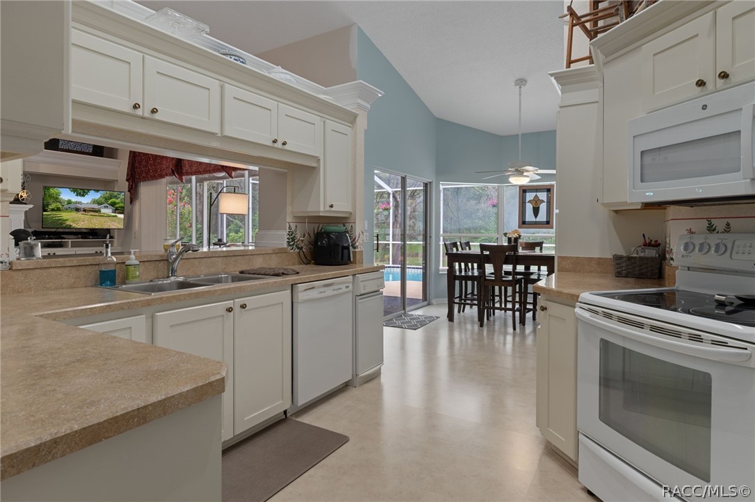 2460 West Pine Ridge Boulevard Beverly Hills, FL 34465 - Photo 11 of 47 a kitchen with stainless steel appliances granite countertop a stove top oven a sink a dining table and chairs