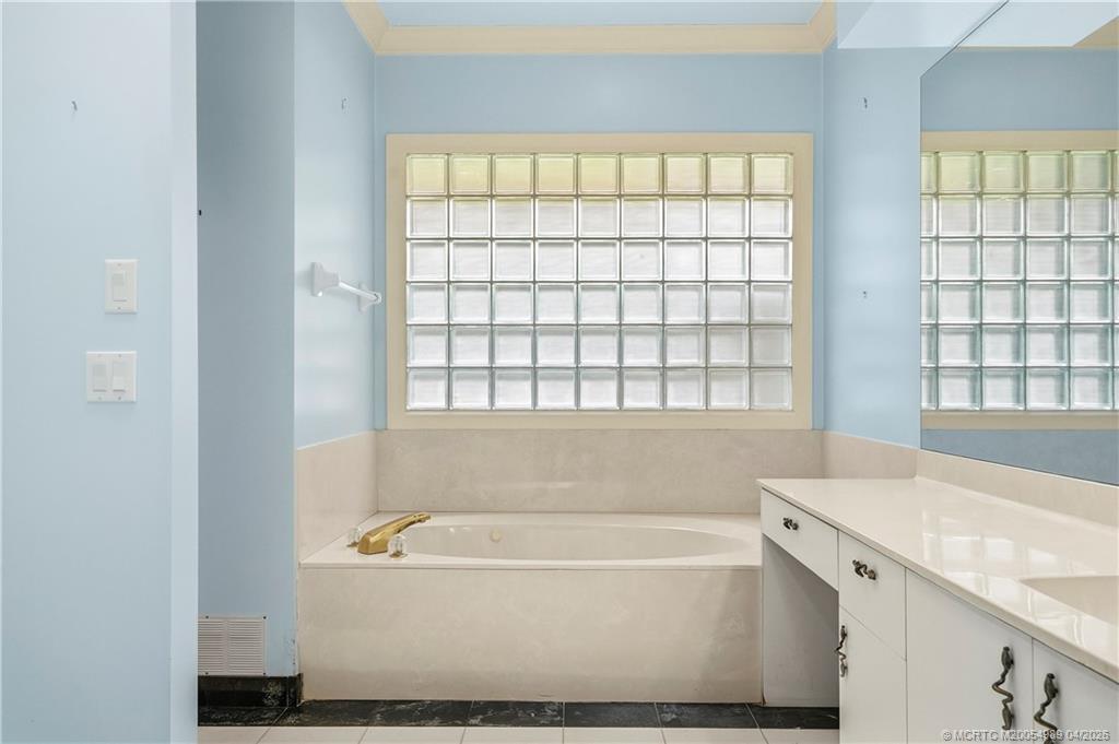 6273 Southeast Baltusrol Terrace Stuart, FL 34997 - Photo 38 of 68 a bathroom with a bathtub and window