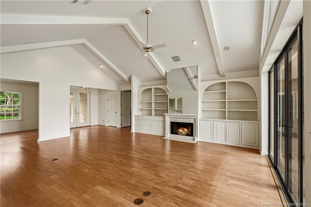 6273 Southeast Baltusrol Terrace Stuart, FL 34997 - Photo 7 of 68 an empty room with wooden floor fireplace and windows