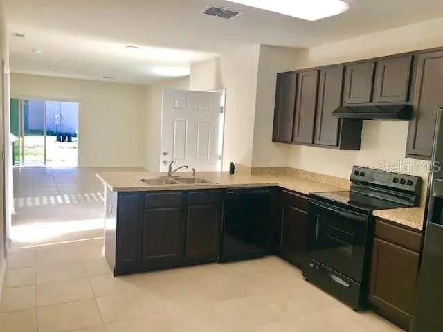 a kitchen with granite countertop a stove a sink and a microwave