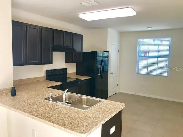a kitchen with a sink a refrigerator and cabinets