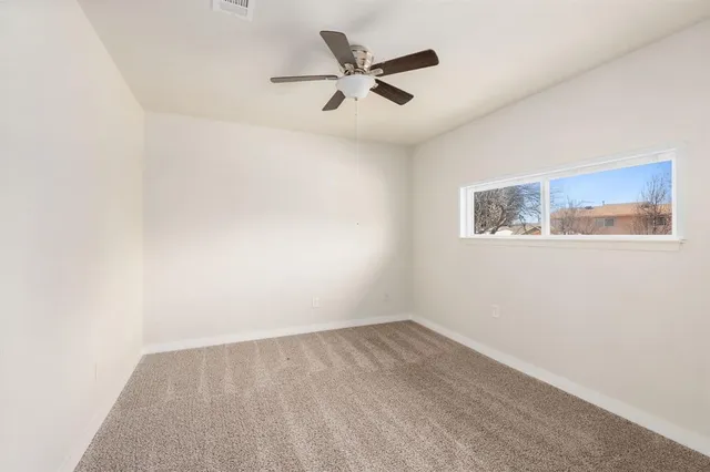 an empty room with a window and a ceiling fan