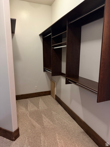 4536 North 475 East Provo, UT 84604 - Photo 41 of 65 Spacious closet featuring built-in dark wood-finish shelving, multiple hanging rods, light-toned carpeting, and coordinated dark wood-finish baseboards