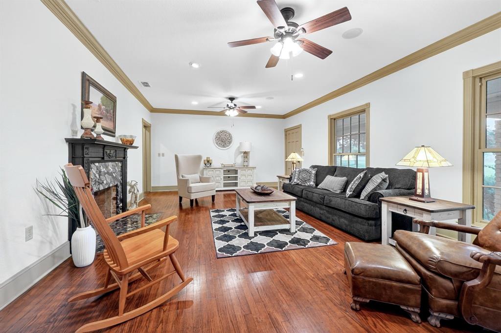 1901 Rose Pointe Athens, TX 75752 - Photo 7 of 37 Spacious living area featuring polished wood-finish flooring, a decorative fireplace with a dark mantel and stone surround, and multiple ceiling fans