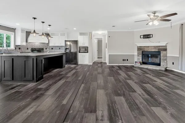 a large kitchen with granite countertop a stove top oven a sink dishwasher and a fireplace with wooden floor