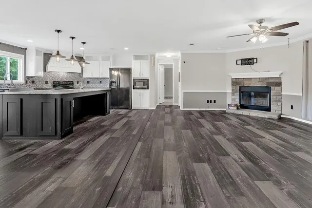 a large kitchen with granite countertop a stove top oven a sink dishwasher and a fireplace with wooden floor