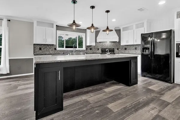 a kitchen with kitchen island granite countertop a sink cabinets and stainless steel appliances