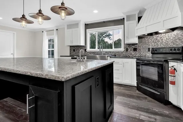 a kitchen with granite countertop kitchen island stainless steel appliances a sink stove and cabinets