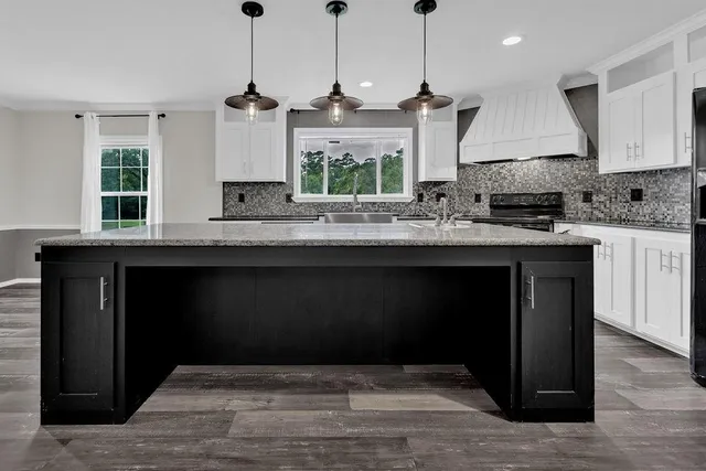 a kitchen with kitchen island granite countertop a stove a sink and a wooden floors