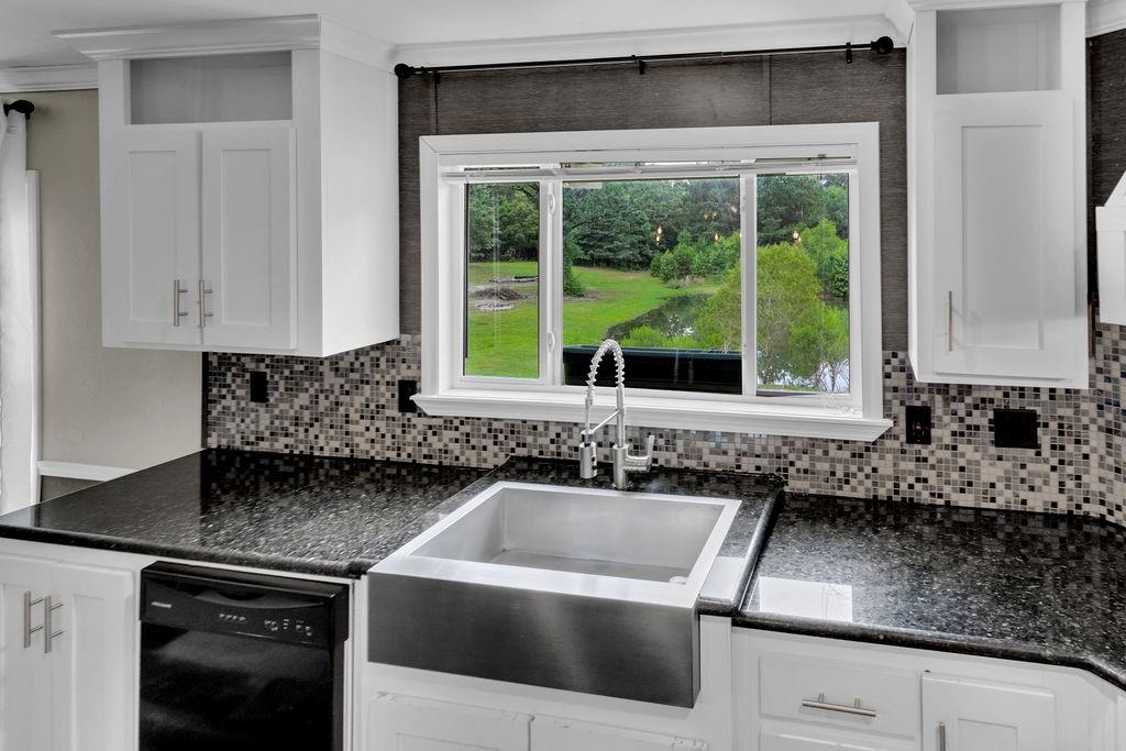 636 Roberson Road Hallsville, TX 75650 - Photo 30 of 36 a kitchen with granite countertop a sink and a white wooden cabinets