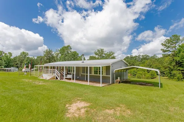 a view of a house with a big yard and large trees