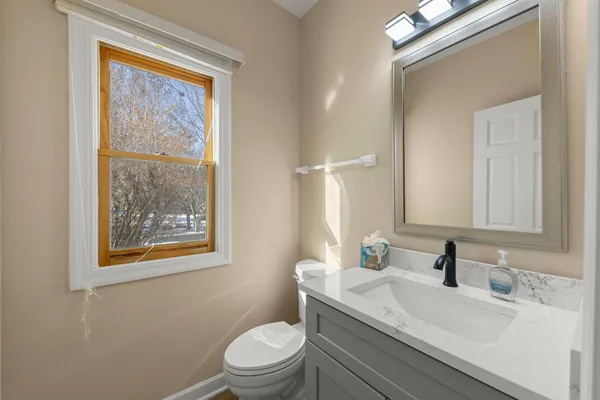a bathroom with a granite countertop toilet a sink a mirror and a window