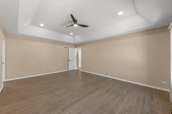 an empty room with wooden floor fan and windows