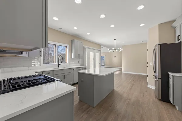 a kitchen with stainless steel appliances a refrigerator a stove a sink and white cabinets with wooden floor