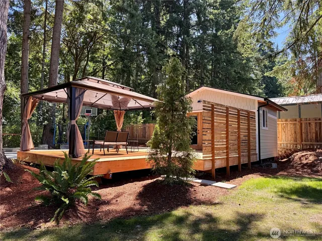a view of a patio with table and chairs under an umbrella with barbeque grill and wooden fence