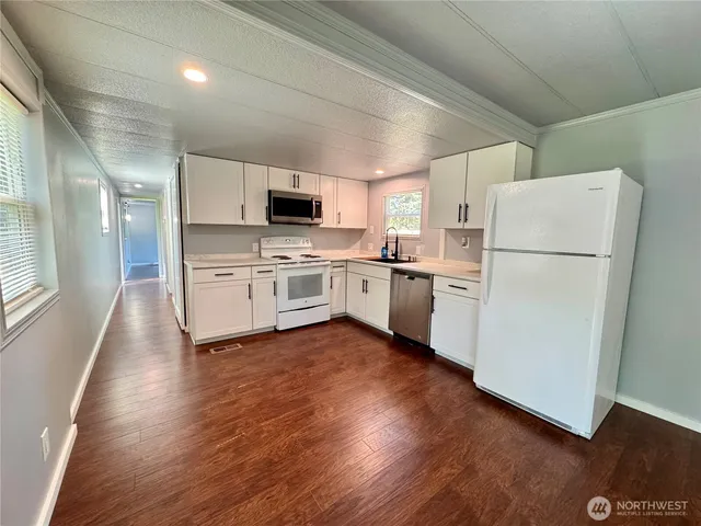 a kitchen with a refrigerator a stove top oven a sink and dishwasher with wooden floor