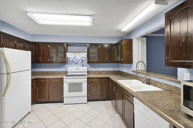 a kitchen with a sink a stove cabinets and wooden floor