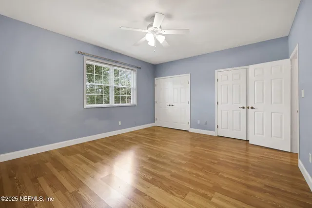 a view of an empty room with a ceiling fan and window