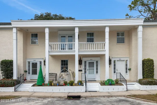 a view of a white house with large windows and plants