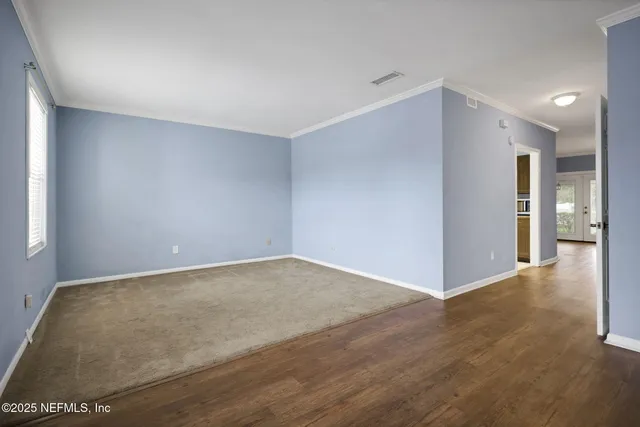 a view of a kitchen from a hallway with wooden floor