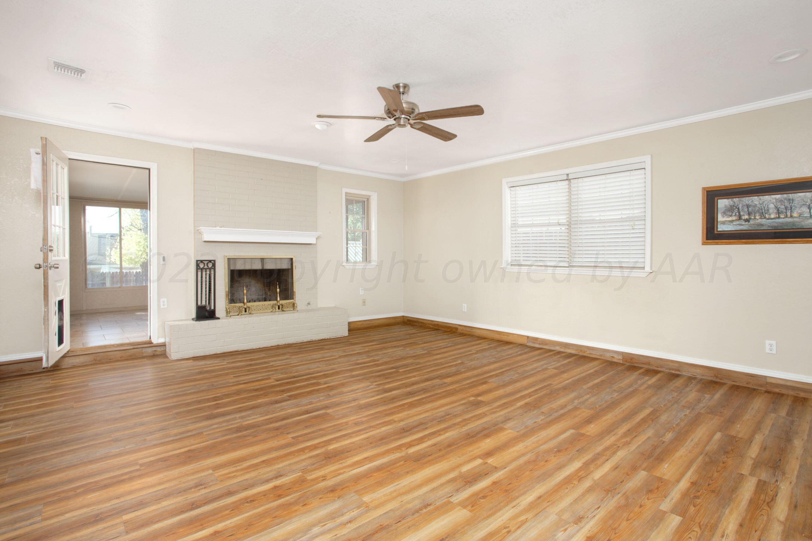 2905 Salem Drive Amarillo, TX 79110 - Photo 4 of 29 an empty room with wooden floor fireplace and windows