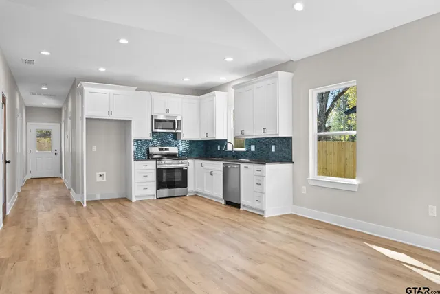 a kitchen with granite countertop a refrigerator and a stove top oven
