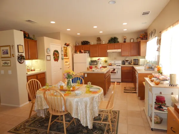 a dining room with stainless steel appliances a dining table chairs refrigerator and sink