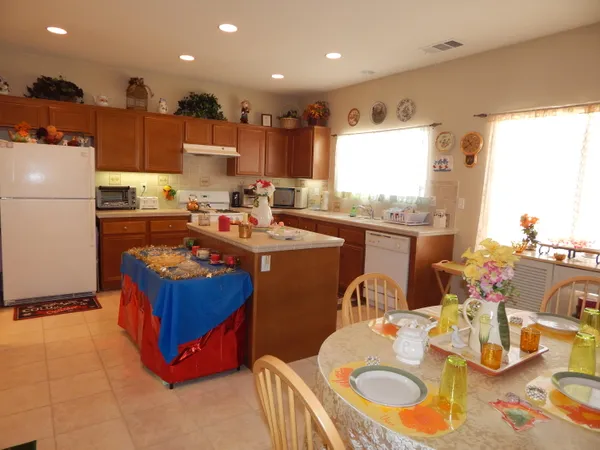 a kitchen with stainless steel appliances granite countertop a sink dishwasher stove refrigerator and couches with wooden floor