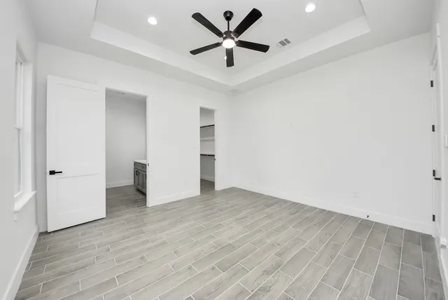 an empty room with wooden floor and a ceiling fan