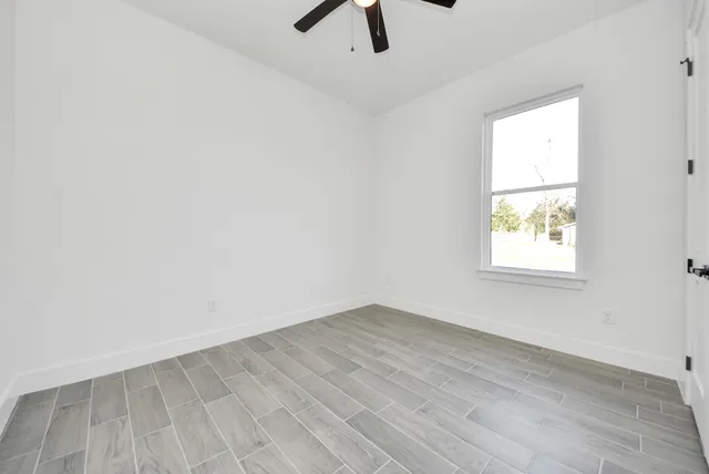 an empty room with a window and a ceiling fan
