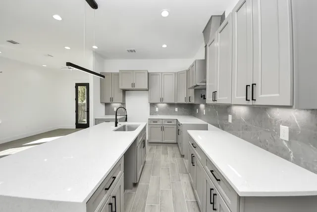 a large kitchen with stainless steel appliances a large counter top a stove and a refrigerator