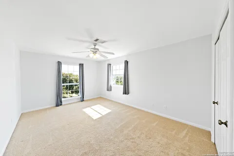 an empty room with windows and chandelier fan