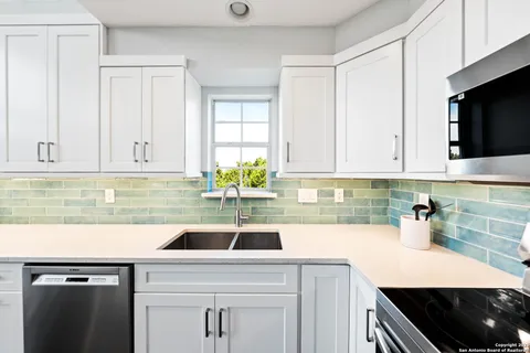 a kitchen with stainless steel appliances white cabinets a sink a stove and a window