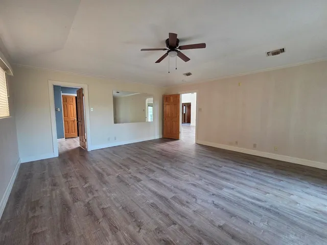 a view of empty room with wooden floor and ceiling fan
