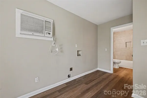 a view of an empty room with wooden floor and a bathroom