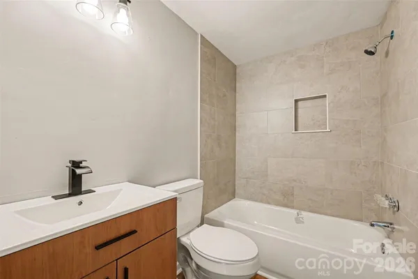 a bathroom with a bathtub shower sink vanity mirror and toilet