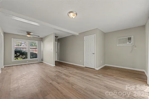a view of an empty room with a window and wooden floor