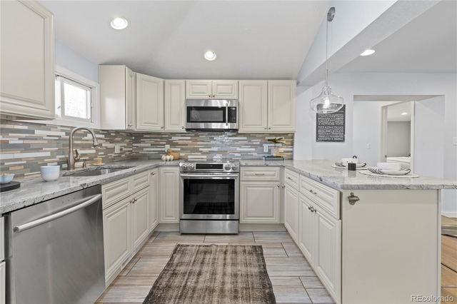 a kitchen with stainless steel appliances granite countertop a sink and dishwasher a stove top oven with white cabinets
