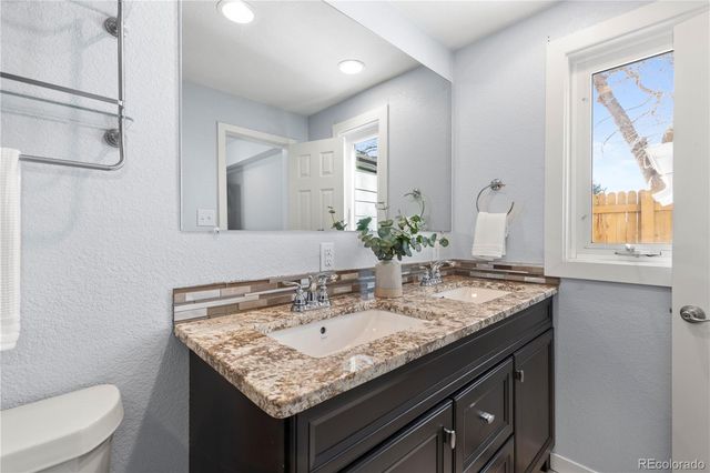 a bathroom with a granite countertop sink a toilet and a mirror