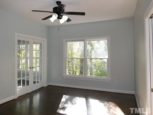 a view of an empty room with wooden floor and a window